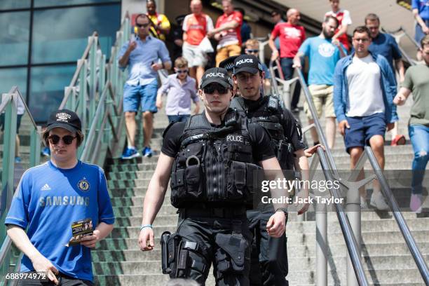 Armed police officers patrol as football fans arrive at Wembley Park Tube Station ahead of the FA Cup final on May 27, 2017 in London, England....