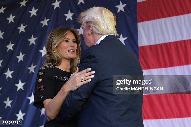 President Donald Trump and US First Lady Melania Trump hug each other on stage during a meeting with US military personnel and families at Naval Air...