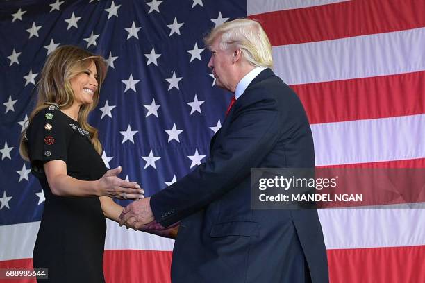 President Donald Trump and US First Lady Melania Trump hug each other on stage during a meeting with US military personnel and families at Naval Air...