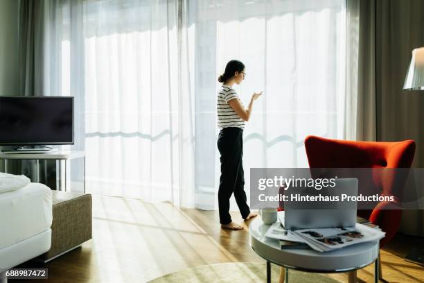 young woman stood in a bright, contemporary hotel room - tv room side imagens e fotografias de stock