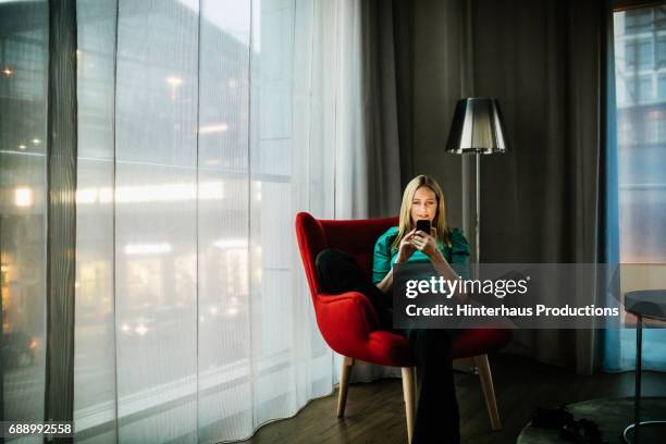 businesswoman talking on smartphone in contemporary hotel room - red chair stock pictures, royalty-free photos & images