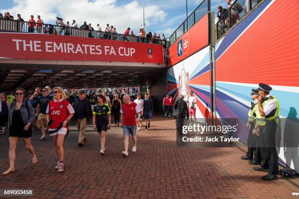 Police officers look on as football fans make their way to Wembley Stadium ahead of the FA Cup final on May 27, 2017 in London, England. Football...