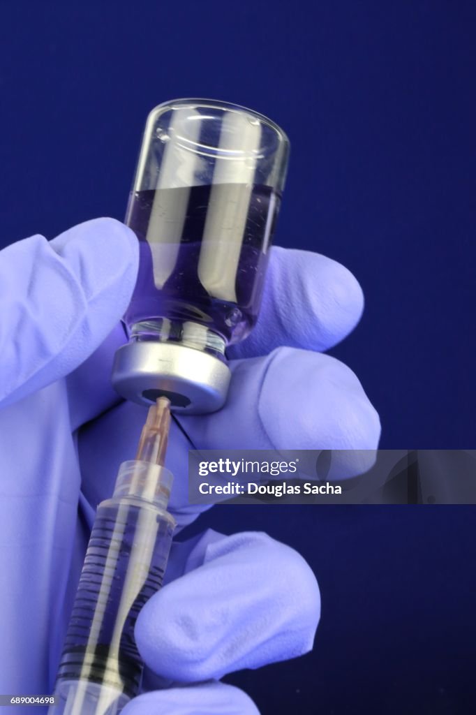 Health worker prepares a Hypodermic needle with Serum Vial