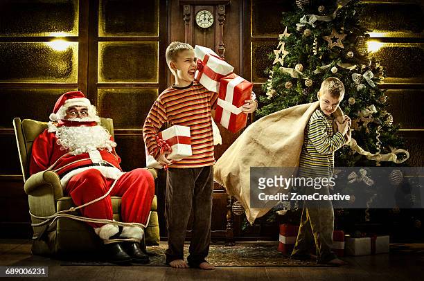 bad children steal santa claus gift - man tied to chair stockfoto's en -beelden