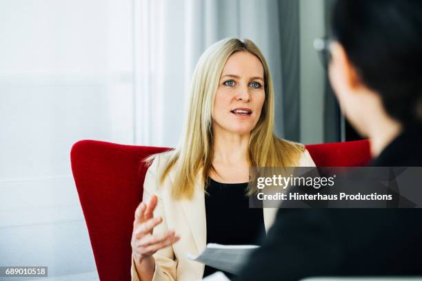 businesswoman exchanging ideas with colleagues - roter mantel stock-fotos und bilder