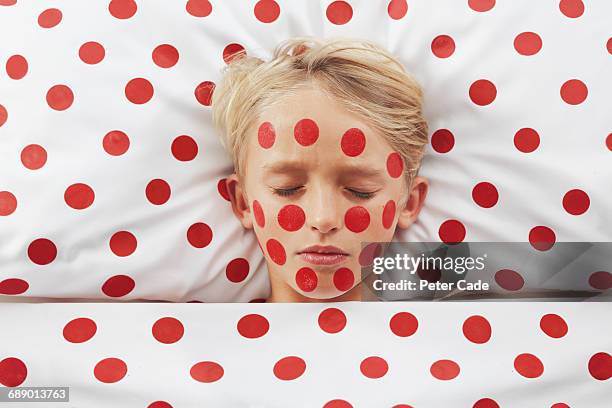 boy with red spots in red spotty bed - dotted human body part stock pictures, royalty-free photos & images