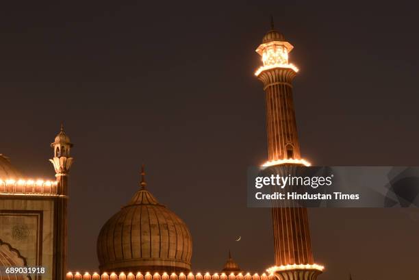 Half Crescent Moon is seen over illuminated Jama Masjid to mark the beginning of the holy fasting month of Ramadan, on May 27, 2017 in New Delhi,...