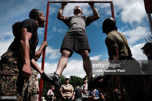 Members of the U.S. Marine Corps watch as Matt Cortright does pull-ups in Brooklyn's Prospect Park as part of Fleet Week on May 27, 2017 in New York...