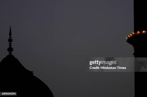 Half Crescent Moon is seen over illuminated Jama Masjid to mark the beginning of the holy fasting month of Ramadan, on May 27, 2017 in New Delhi,...