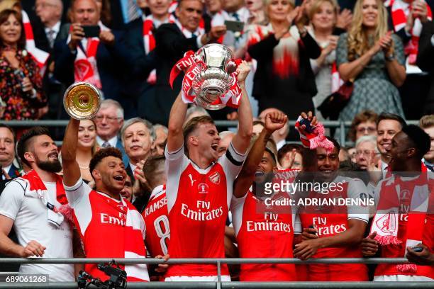 Arsenal's English defender Rob Holding lifts the FA Cup trophy as Arsenal players celebrate their victory over Chelsea in the English FA Cup final...