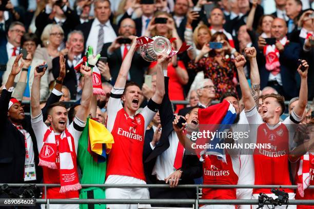 Arsenal's German defender Per Mertesacker lifts the FA Cup trophy as Arsenal players celebrate their victory over Chelsea in the English FA Cup final...