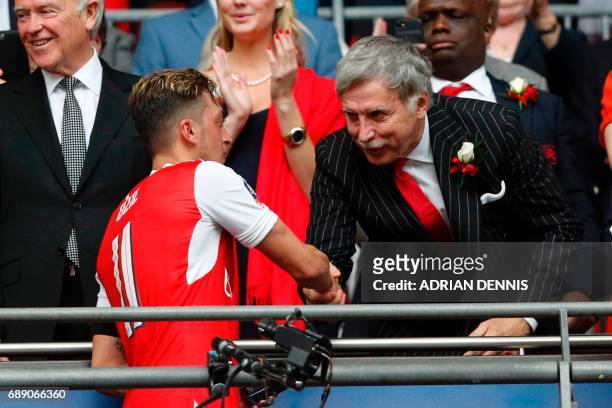 Arsenal's US owner Stan Kroenke shakes hands with Arsenal's German midfielder Mesut Ozil as Arsenal players celebrate their victory over Chelsea in...