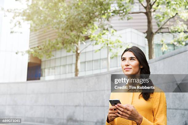 woman looking up with mobile - yellow shirt stock pictures, royalty-free photos & images
