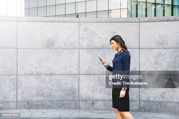 woman walking with mobile - boundary wall stock pictures, royalty-free photos & images