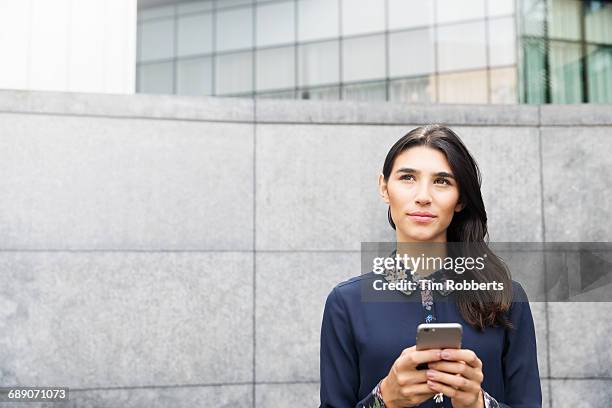 woman looking up with mobile phone. - certain stock pictures, royalty-free photos & images