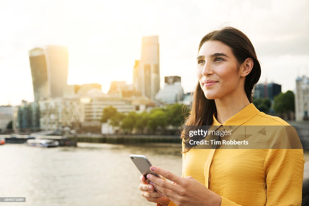 Woman looking up with mobile phone, sunset