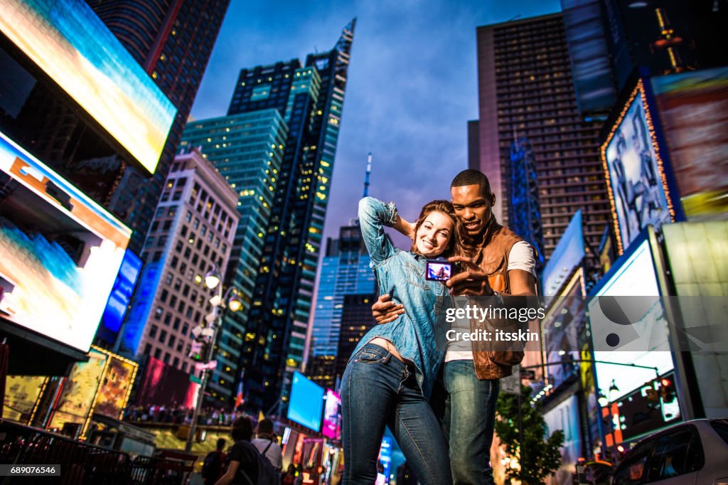 Casal de raça mista andando em New York City, tendo selfies