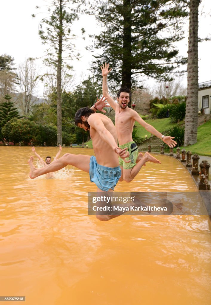 Friends having fun and jumping into volcanic hot springs