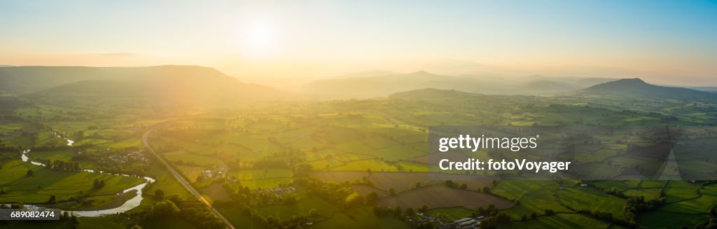 Golden sunset aerial panorama over idyllic green summer countryside mountains
