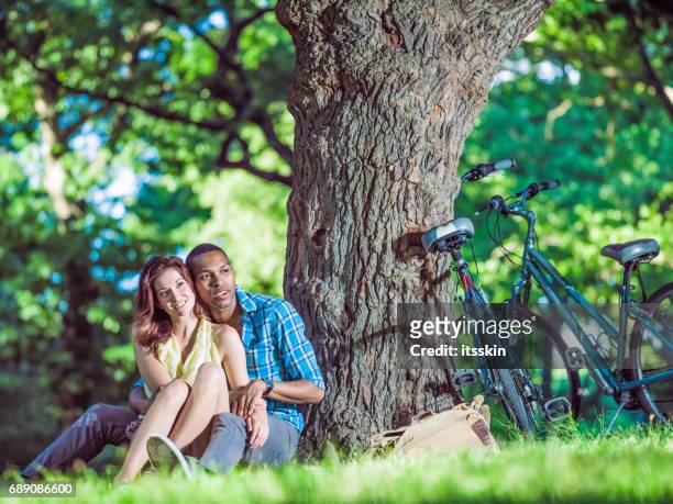 mixed race couple relaxing in central park, new york - couple central park stock pictures, royalty-free photos & images