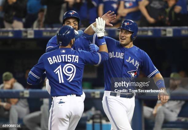 Jose Bautista of the Toronto Blue Jays is congratulated by Luke Maile and Devon Travis after hitting a three-run home run in the fifth inning during...