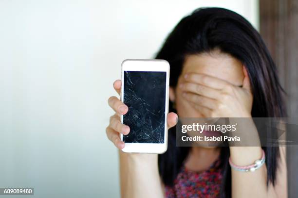 shocked woman holding broken smart phone - fratura imagens e fotografias de stock