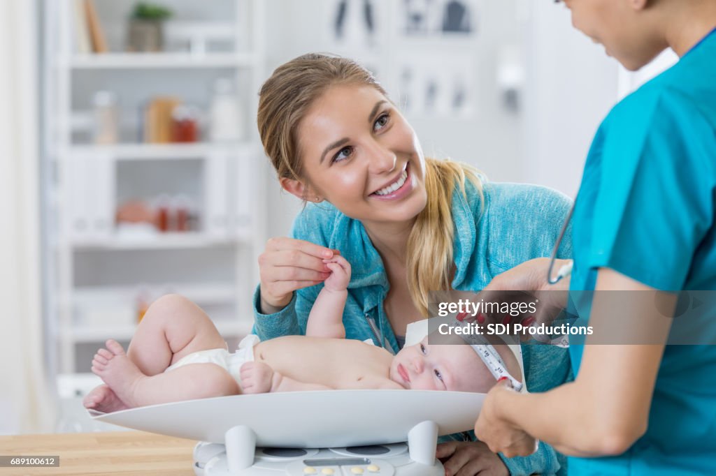 Nieuwe moeder praat met verpleegkundige tijdens haar baby's goed controleren