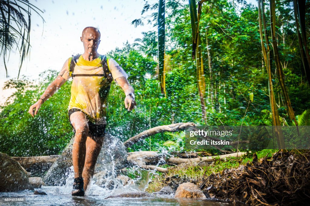 Un hombre correr por el bosque tropical