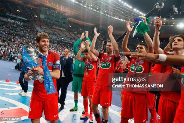 Paris Saint-Germain's Brazilian defender Maxwell holds the trophy as he and teammates celebrate after winning the French Cup final football match...