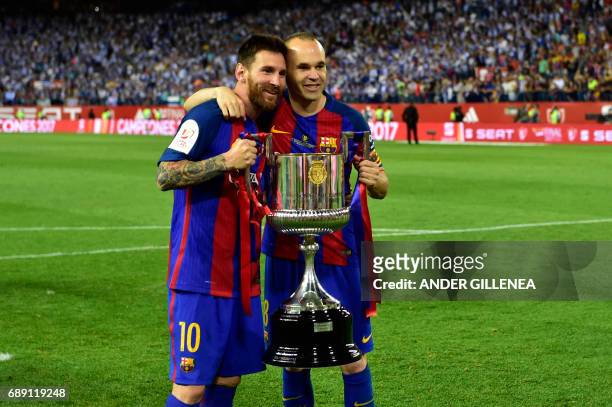 Barcelona's Argentinian forward Lionel Messi and Barcelona's midfielder Andres Iniesta hold up the trophy after the team won the Spanish Copa del Rey...