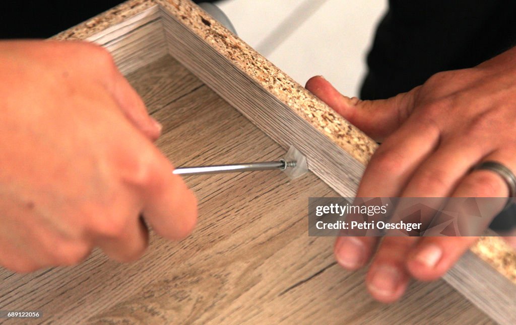 A Young man building a cabinet.