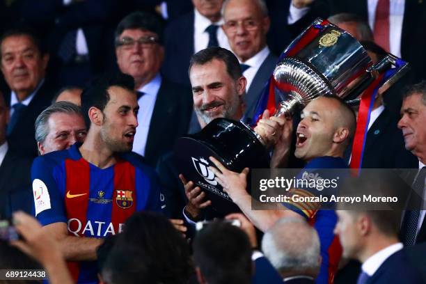 King Felipe VI of Spain gives the Cup to captain Andres Iniesta of FC Barcelona and his teammate Sergio Busquets Burgos after winning the Copa Del...
