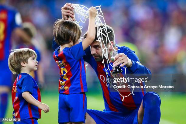 Gerard Pique of FC Barcelona gives his son Milan a piece of the goal's net after winning the Copa Del Rey Final between FC Barcelona and Deportivo...