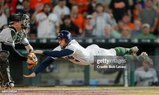 George Springer of the Houston Astros scores in the first inning as he dives past he tag of Caleb Joseph of the Baltimore Orioles in the first inning...