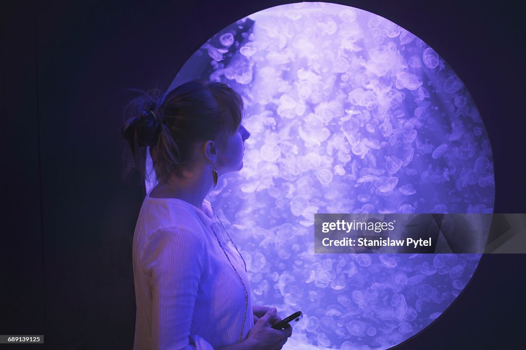 Woman looking at jellyfishes in aquarium