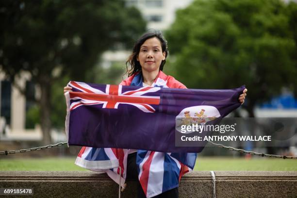 In this picture taken on May 18 artist and designer Alice Lai who heads a small protest group called HK-UK Reunification Campaign, holds the old...