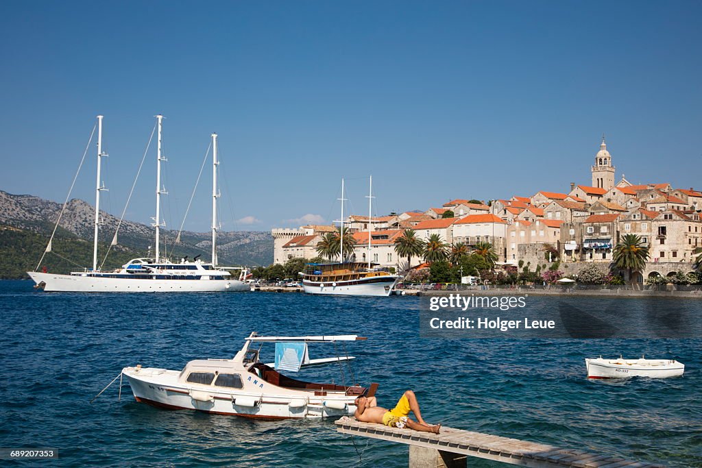 Man relaxes on jetty with Korcula Old Town behind