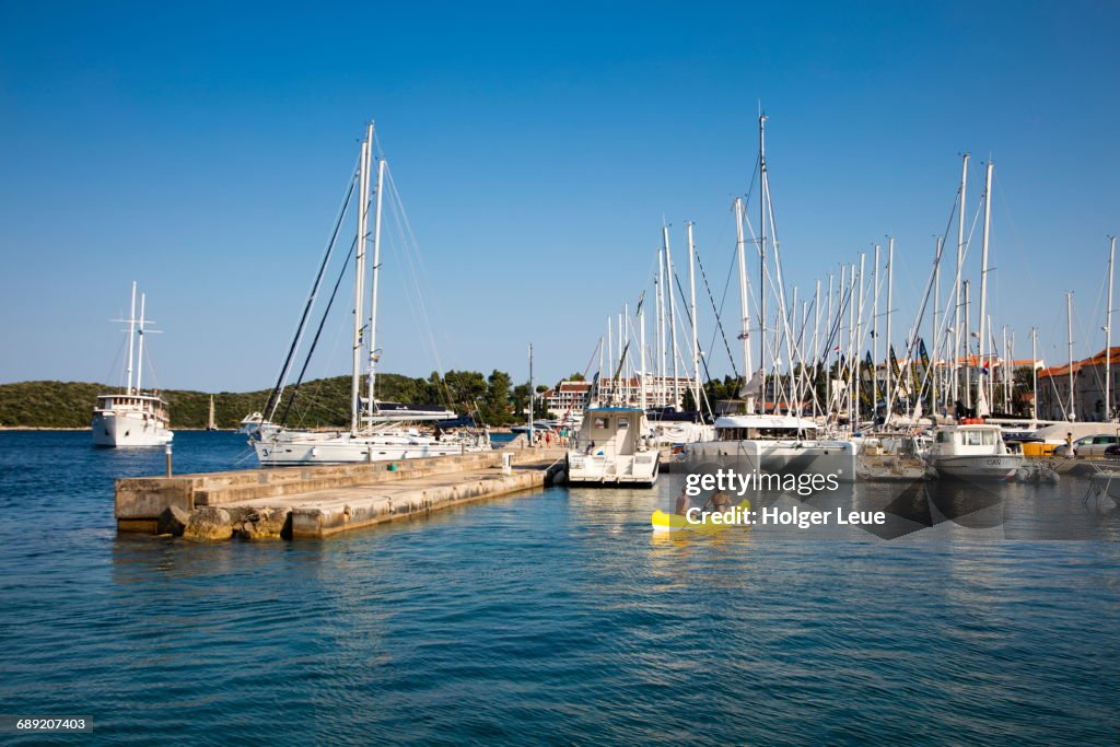 Couple in yellow canoe and sailboats in marina