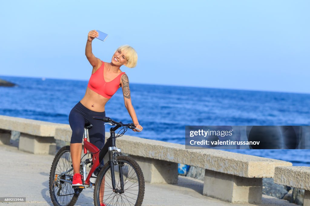 Blong woman riding a bike and taking selfie