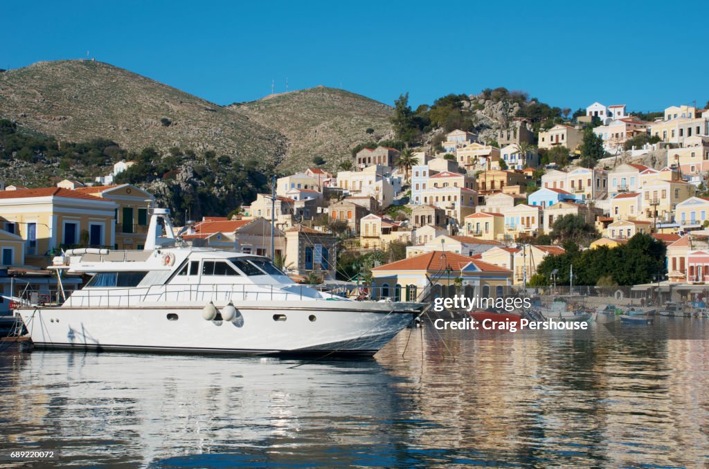 Boats in Symi Harbour before pastel-coloured houses.