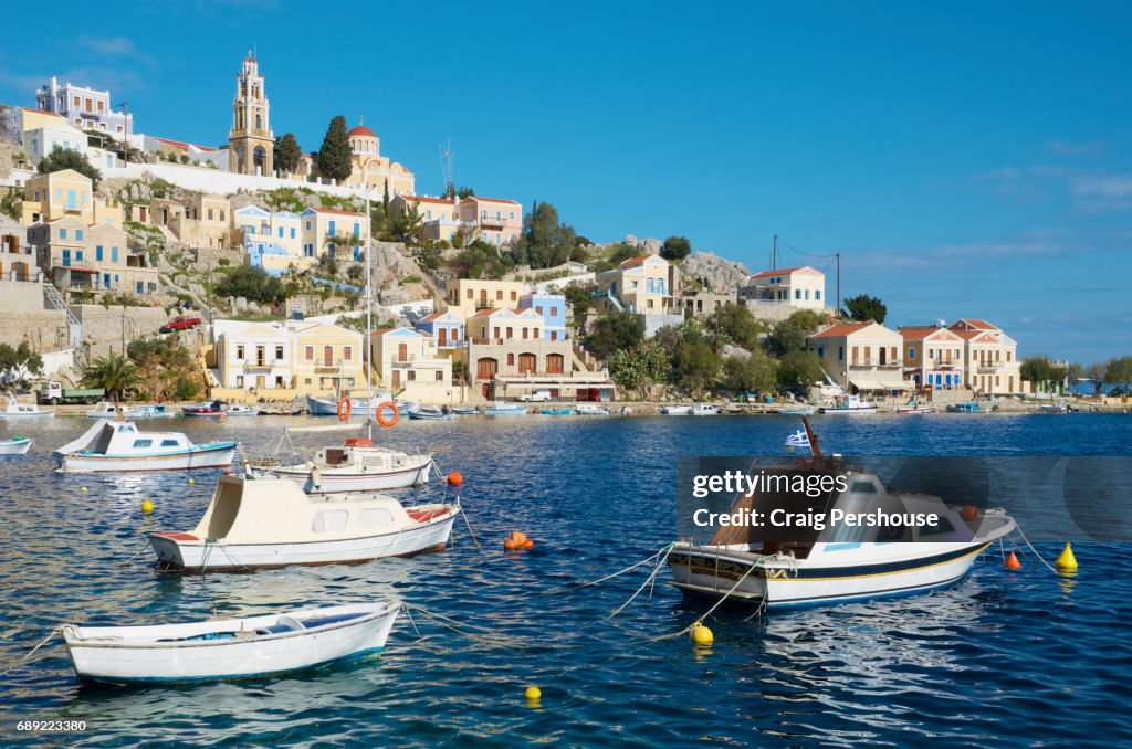 Boats in Symi Harbour before pastel-coloured houses and Ekklisia Evaggelistria (Annunciation Church).