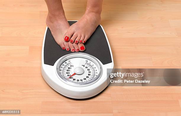 obese woman weighing herself - preocupación por el cuerpo fotografías e imágenes de stock
