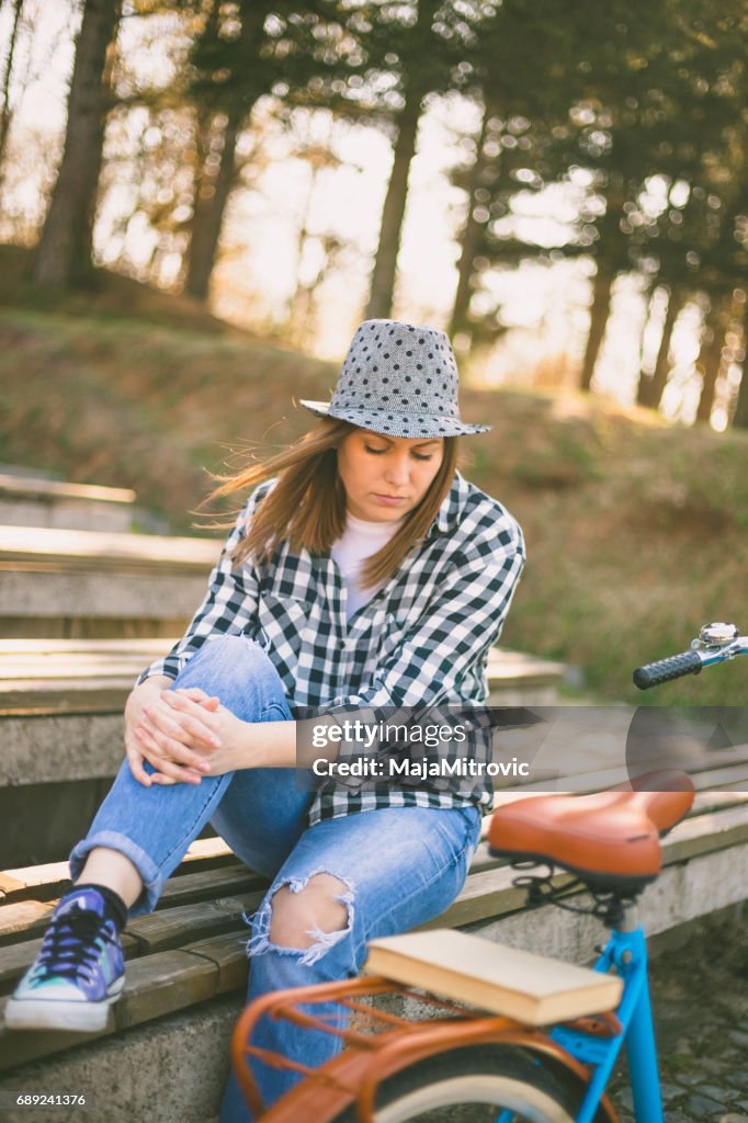 Young beautiful woman sitting on bench in park. Nature environment background.