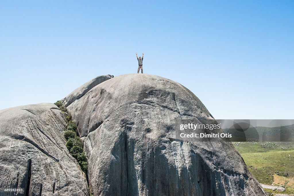 Man standing on summit of huge rock