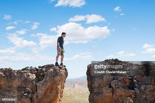 man deliberating at a crevice. - edge of cliff stock pictures, royalty-free photos & images