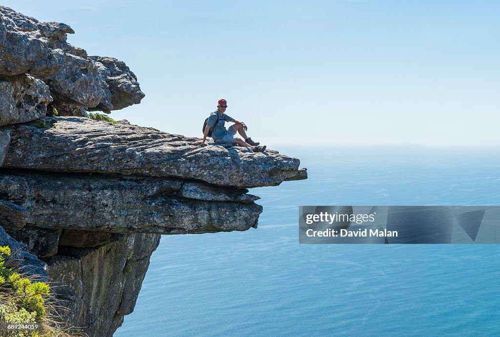 Man sitting on a rock ledge.