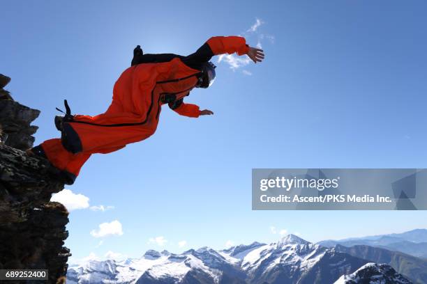 wingsuit flyer jumps from cliff edge, mountains - base jumping imagens e fotografias de stock