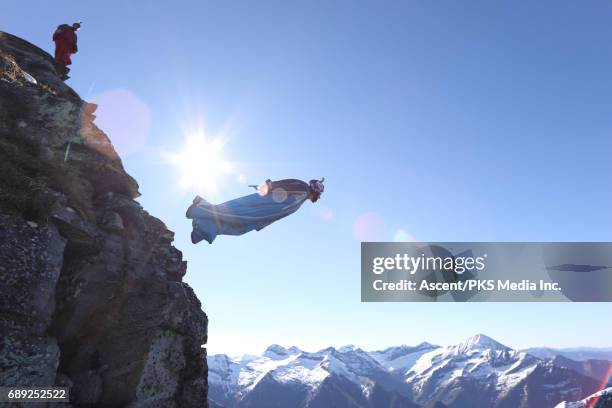 wingsuit flyer jumps from cliff edge, mountains - base jumping stock pictures, royalty-free photos & images