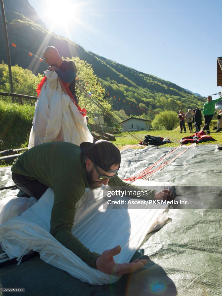 Wingsuit flyer folds landing chute before jump