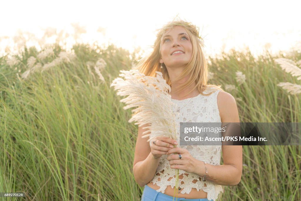 Young woman pauses in field of rushes, sunrise